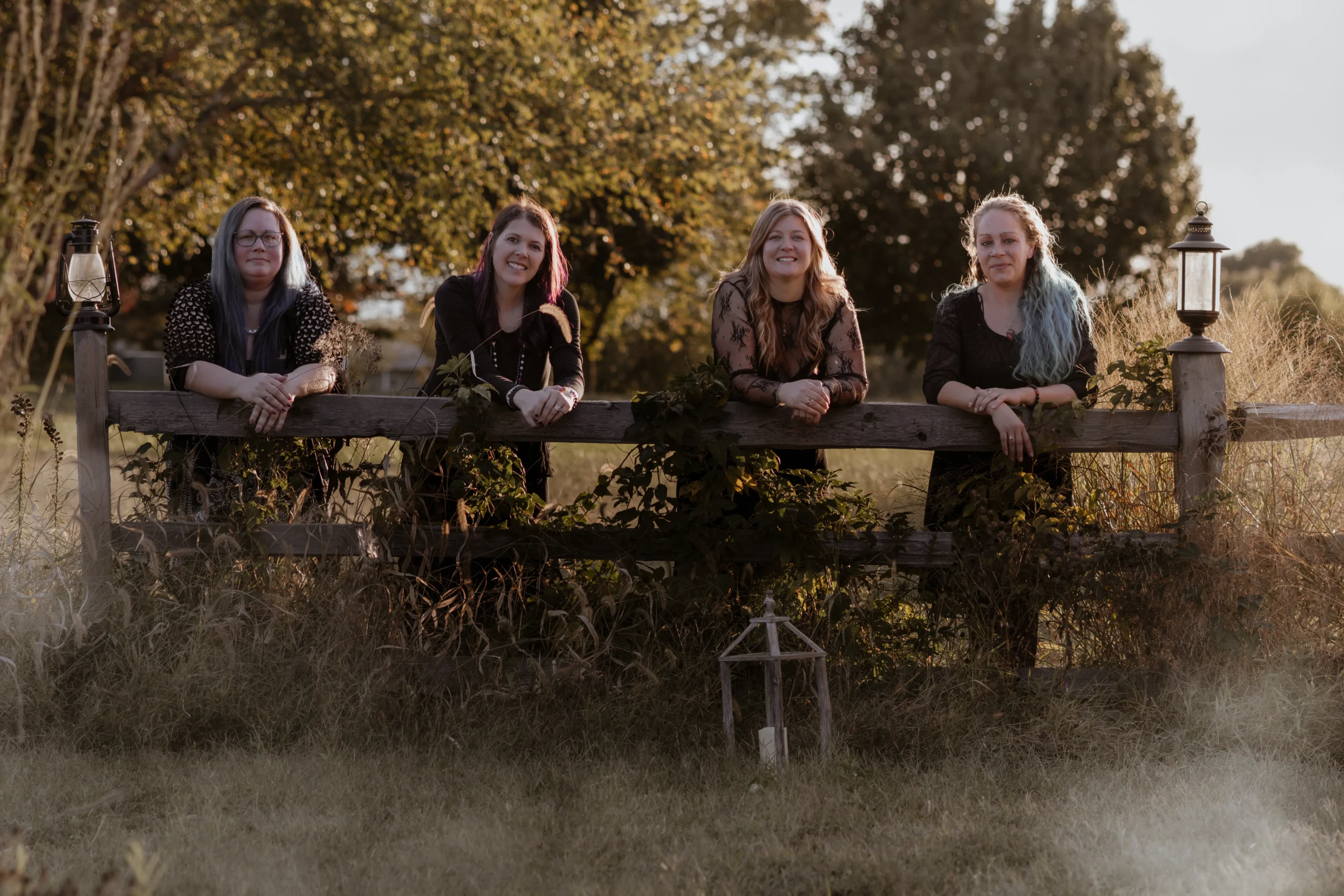 The four Mystic Sisters gathered outdoors beside a rustic wooden fence.
